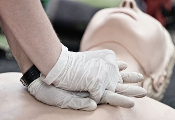 Person performing CPR wearing gloves