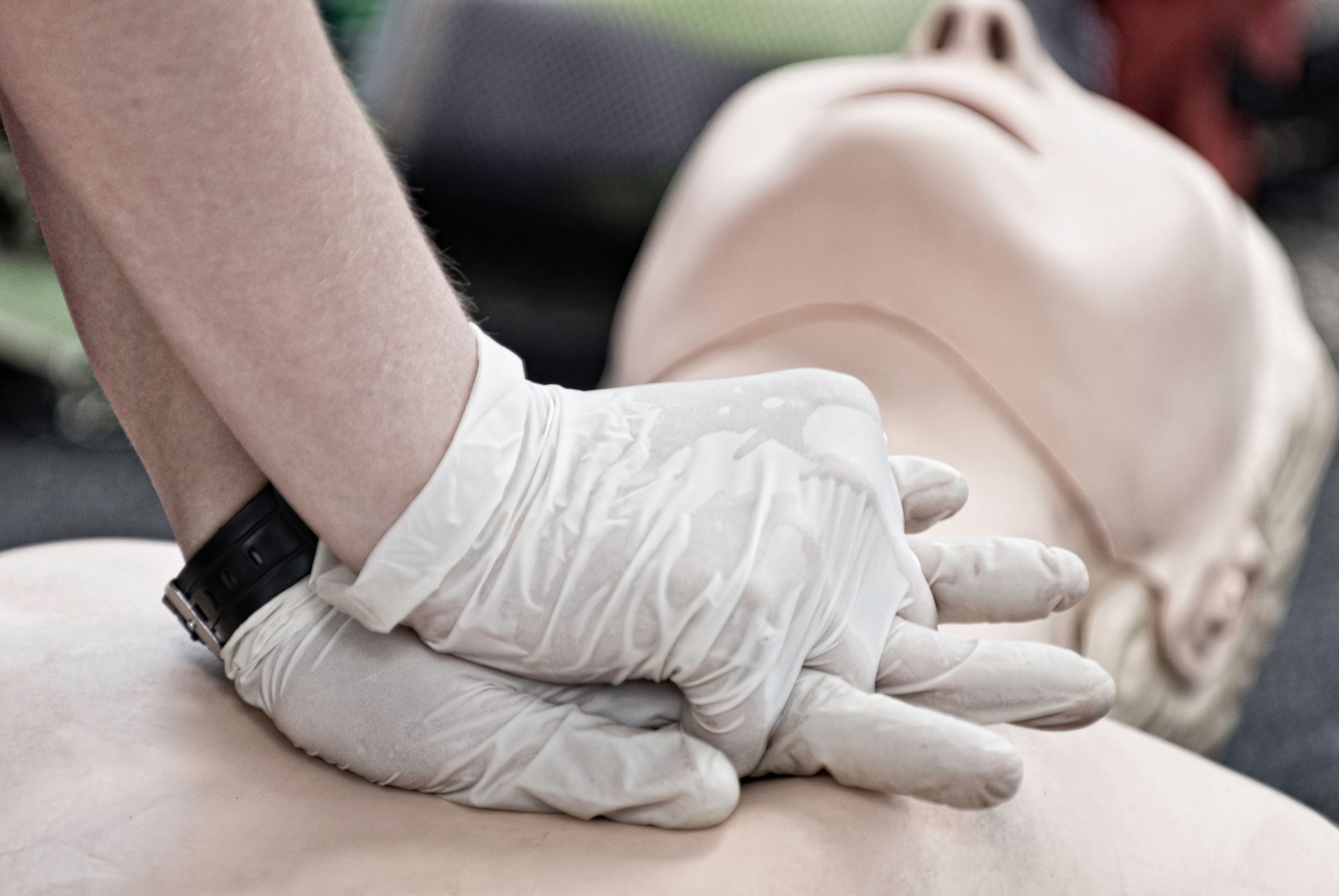 Person performing CPR wearing gloves