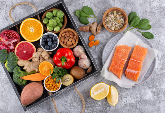 Assorted healthy foods with salmon, fruits, and vegetables.