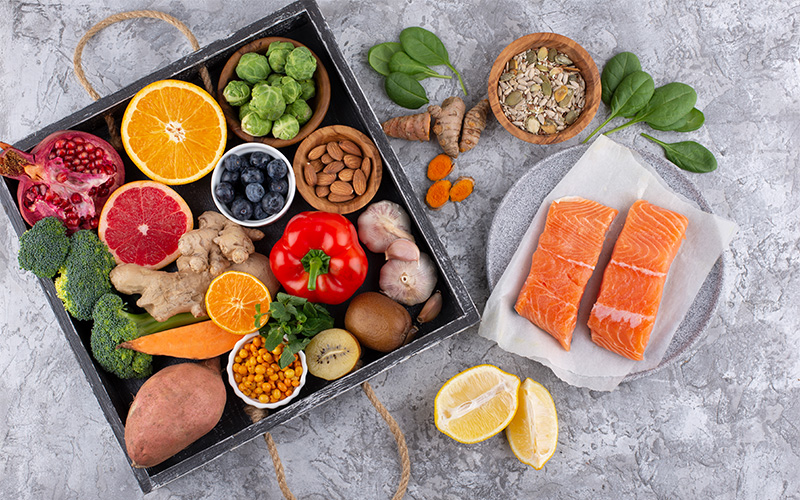Assorted healthy foods with salmon, fruits, and vegetables.