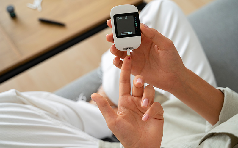 Patient using a glucose meter to monitor blood sugar levels.