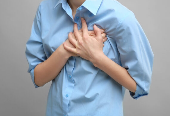 Woman clutching her chest in pain due to rapid heartbeat.