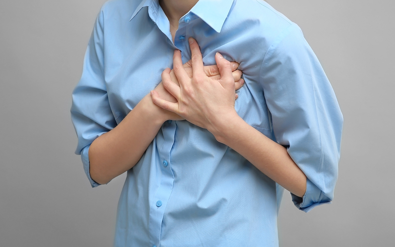 Woman clutching her chest in pain due to rapid heartbeat.