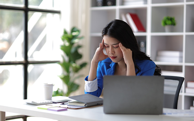 Woman experiencing fatigue and headaches, potential symptoms of diabetes.