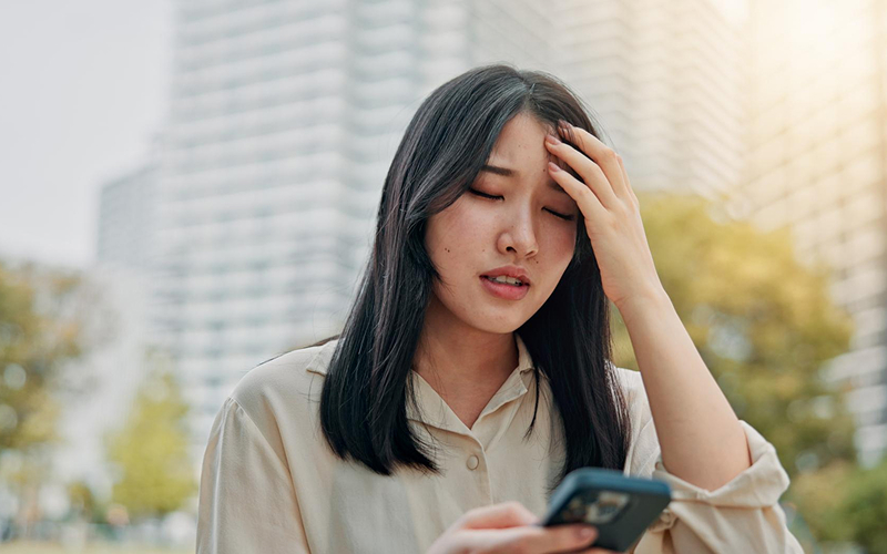 Woman feeling dizzy and lightheaded while using her smartphone.