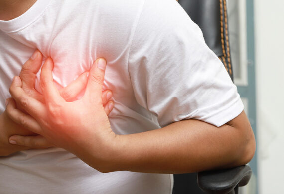 Man clutching chest experiencing sharp pain from potential heart failure.