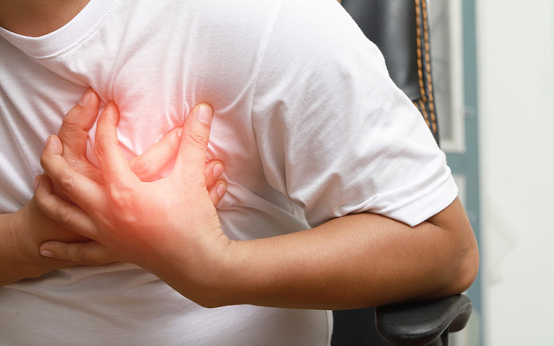 Man clutching chest experiencing sharp pain from potential heart failure.
