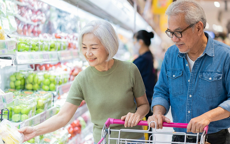 Singapore elderly couple selecting healthy, nutrient-rich food at the supermarket.