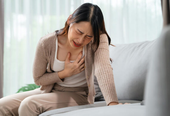 Woman clutching her chest while experiencing a heart attack.