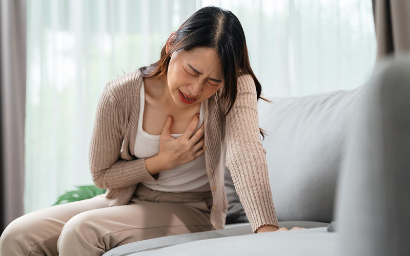 Woman clutching her chest while experiencing a heart attack.