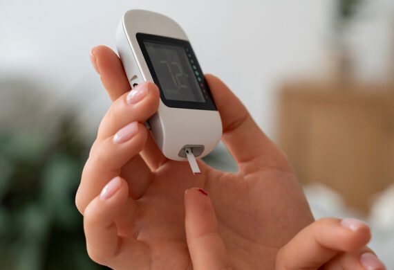 Hands checking blood sugar level with a digital glucometer.