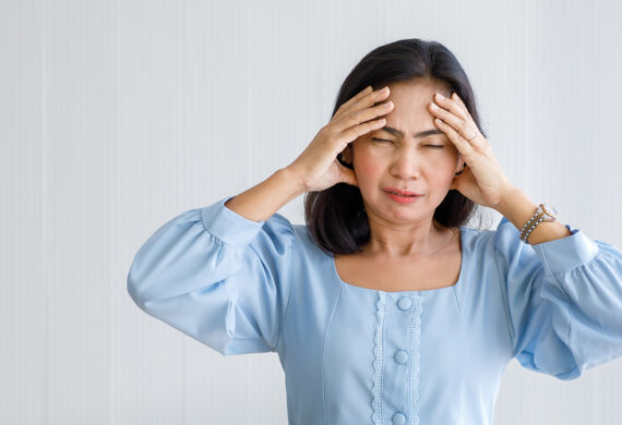 Woman clutching head experiencing sudden headache, a stroke sign.