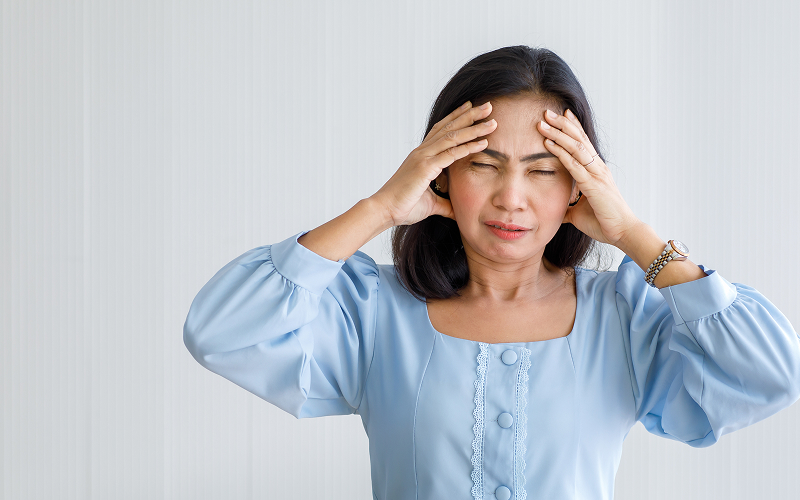 Woman clutching head experiencing sudden headache, a stroke sign.