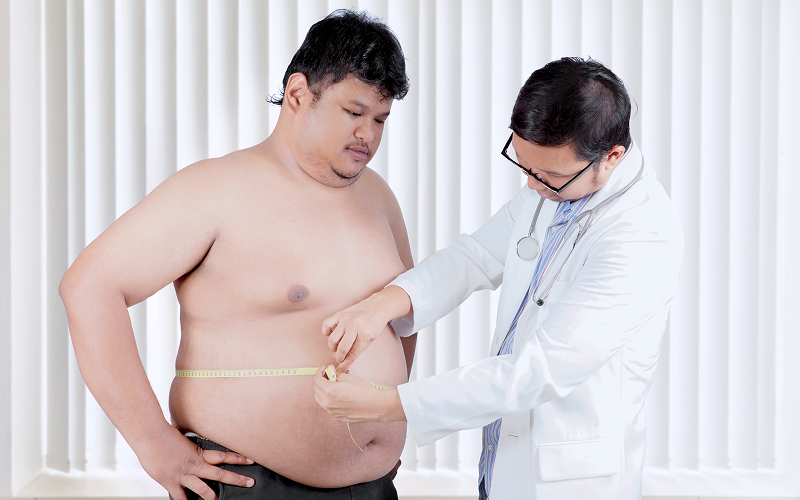 Doctor measuring waist of a man with diabetes.
