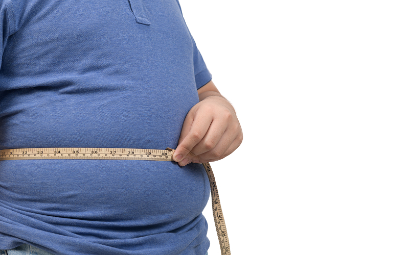 Man measuring waist size indicating metabolic health risk factors.