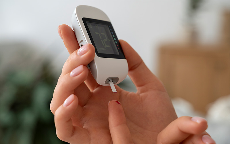 Hand holding glucose meter showing 72 mgdL.