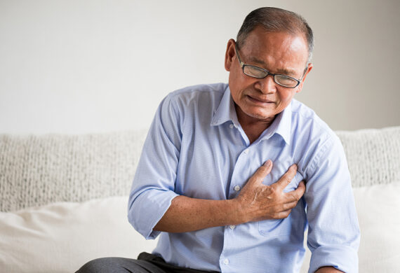 Elderly man clutching chest experiencing symptoms of heart disease