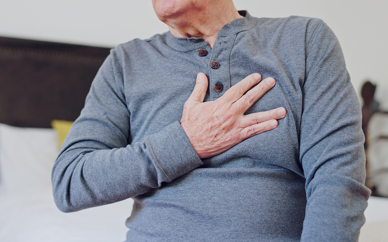 Senior man clutching chest in pain from coronary heart disease